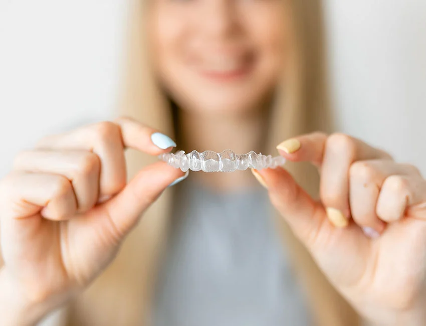 Happy Patient holding Invisalign® clear aligners